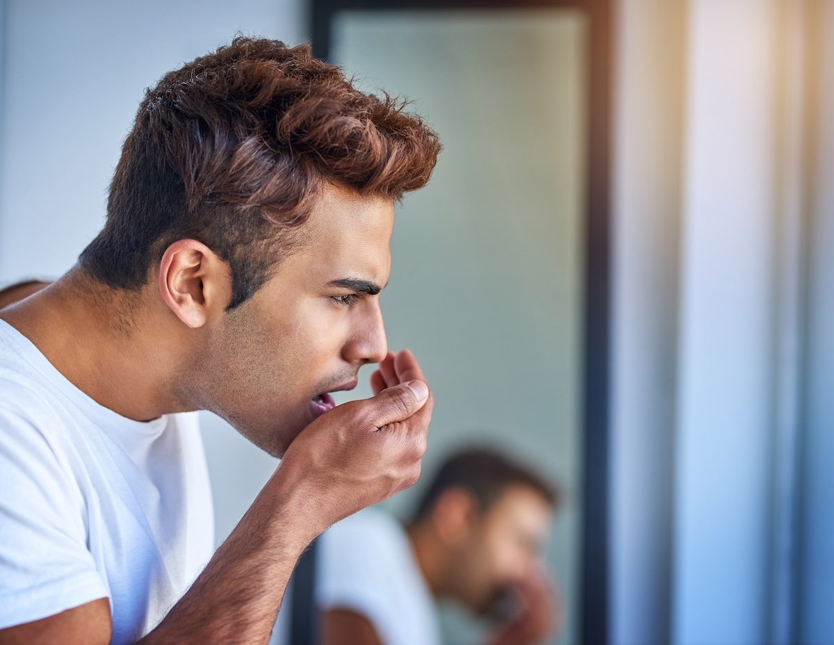Man checking his breath in the mirror, highlighting symptoms related to The Link Between Diabetes and Periodontal Disease.